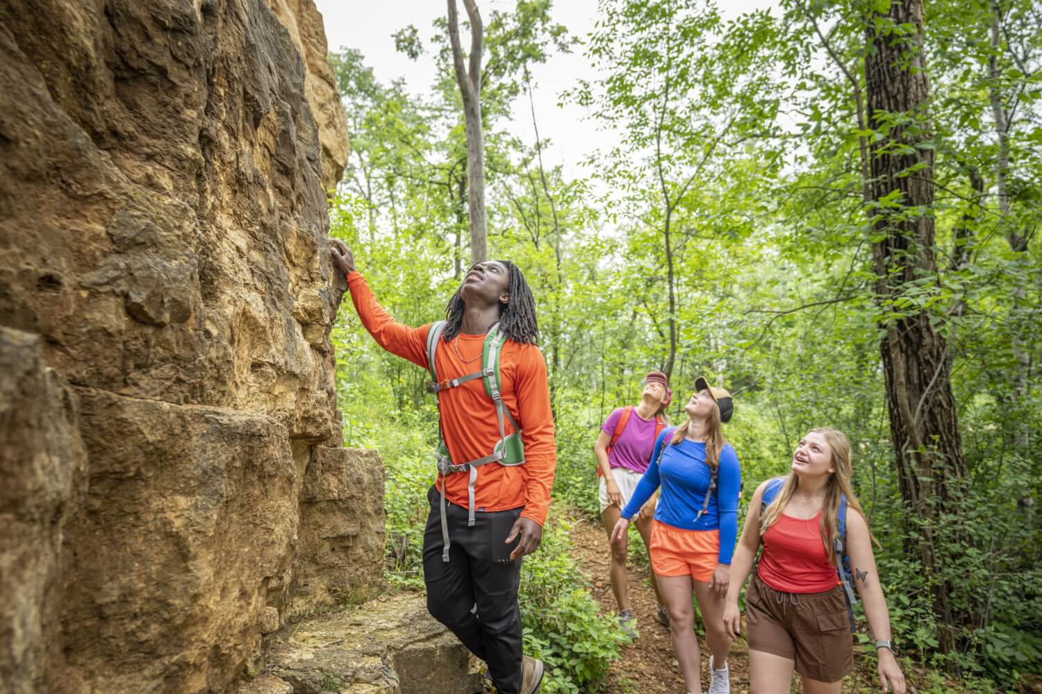 four people hiking in the bluffs looking up at the rock formations